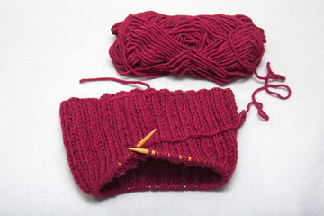 The process of knitting a scarf-snud on circular wooden knitting needles from red wool, warm winter asseksuar