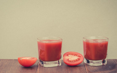 two glasses of tomato juice on a wooden table/two glasses of juice and two tomatoes