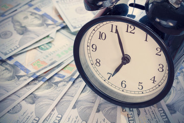 Old fashioned alarm clock on dollar banknotes with copy space