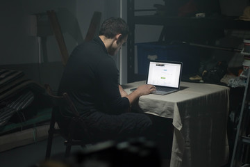 Man using laptop in dark room.