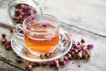 Tea made from tea rose petals in a glass bowl on wooden  background