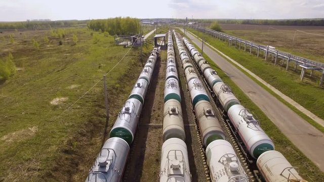 Railroad yard with trains with tanks amidst the fields. Aerial view
