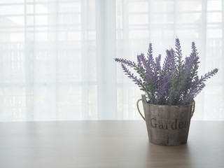 wood table with left free space and purple lavender flowerpot on beautiful white drape window texture background.