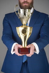 champion cup, golden reward in hand of man or businessman