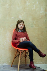 Pretty girl sitting on chair with piggy bank