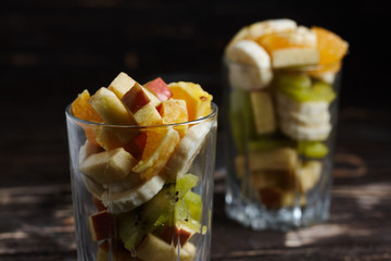 Fruit desserts made at home. 2 cups with sliced fruit. Fresh fruits on a wooden background.