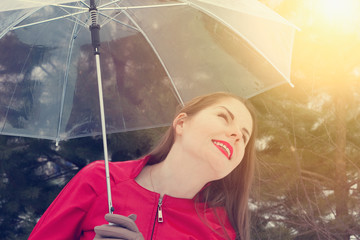Smiling young woman under transparent umbrella