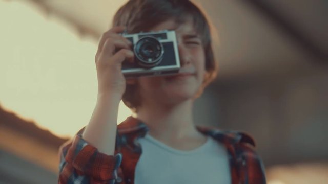 boy taking photo with an old film camera. shot in slow motion