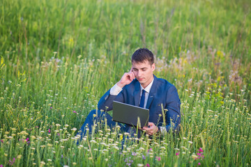 Naklejka na ściany i meble Businessman in the field, with a laptop.