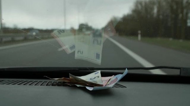 Euro money placed inside the moving car windshield. Close up.