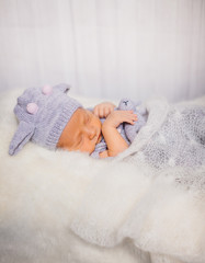 Dreamy little baby in blue cow suit on white fluffy pillow
