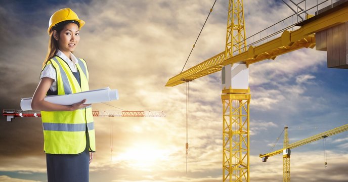Female architect holding blueprint by cranes 