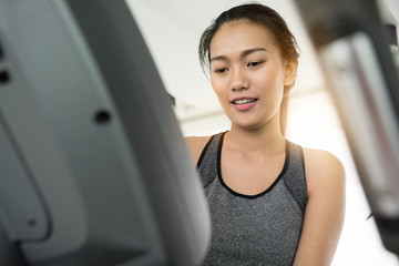Asian woman in sportswear using treadmill at the gym.