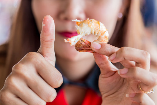 Woman eating grilled prawn fresh from the farm.