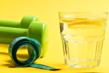 overweight with dumbbells, measuring tape and water with lemon