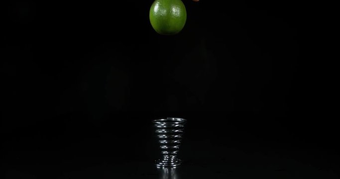 Green Lemon, citrus aurantifolia, Fruit that Rebounds on an Egg Cup on Black Background, Slow Motion 4K