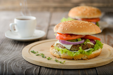Fresh hamburger on cutting board with cup of coffee