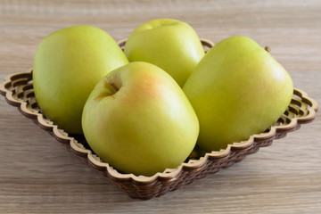 Yellow apples in a basket on the table.