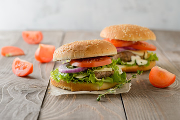 Home made hamburger with beef, onion, tomato, lettuce and cheese. Fresh burger closeup on wooden rustic table