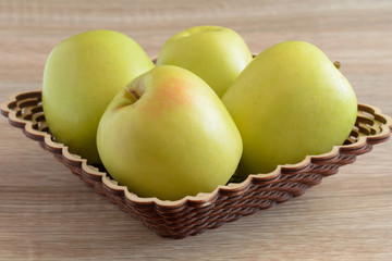 Yellow apples in a basket on the table.