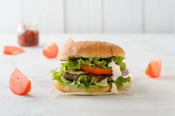 Beef burger, hamburger with tomatoes, grilled meat on a white table
