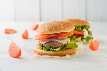Beef burger, hamburger with tomatoes, grilled meat on a white table