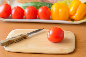 Tomatoes and cucumbers and peppers cutting board on the table.