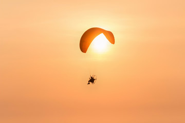 silhouette paramotor with sunset on the orang sky in the evening:ideal use for background