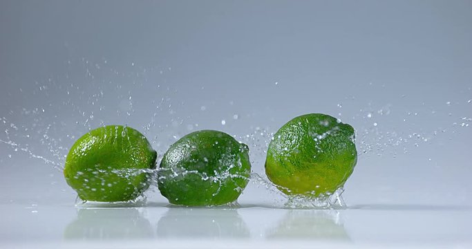 Green Lemons, citrus aurantifolia , Fruit falling on Water, Slow Motion 4K