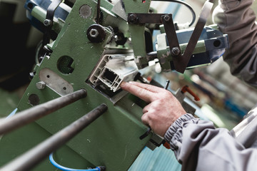Manual worker cutting aluminum and PVC profiles. Manufacturing jobs. Selective focus. Factory for aluminum and PVC windows and doors production.