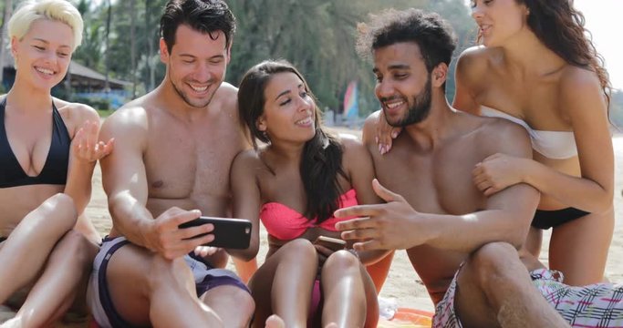 People Sit On Beach Use Cell Smartphone Talking, Young Happy Man And Woman Group On Vacation Communication Tourists On Summer Holiday Slow Motion 60