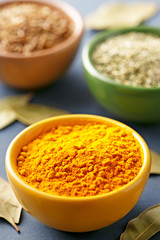 Spices in colorful bowls viewed from above. Various seasonings on a dark background. Cumin, curry powder, oregano. 