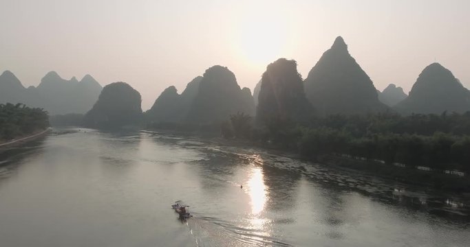 Aerial shot of passenger boats,rafts in beautiful Li River surrounded by karst mountains at sunset or sunrise in Yangshuo,Guilin,China. Travel, picturesque famous destination and adventure concept.