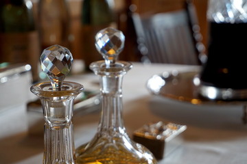 Old glass wine and spirit decanters on an ornate table in natural daylight