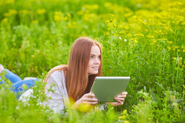 Smiling girl with laptop on grass