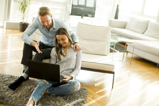 Couple sitting on the floor with laptop in the living room