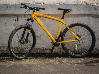 Fototapeta na wymiar the yellow bike leaning against an old concrete wall