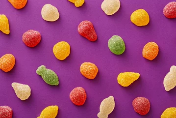 Crédence de cuisine en verre imprimé Bonbons Colorful gummy candies pattern on a purple background. Soft gums in fruit shapes viewed from above. Variation concept. Top view