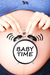 It’s time to have a baby with pregnant belly and classic alarm clock spelling “baby time”