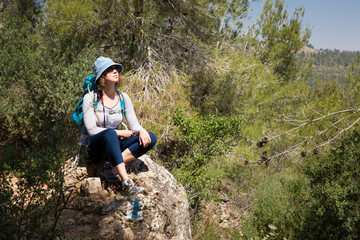 Woman tourist backpacker sitting resting stone hiking forest landscape.
