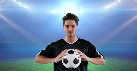 Confident player holding soccer ball at stadium