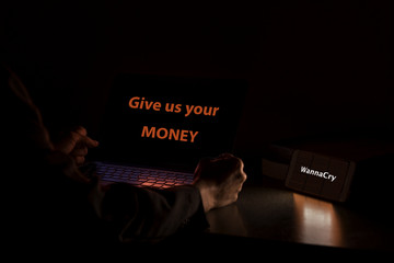 Young Asian male frustrated, confused and clenched hand by WannaCry ransomware attack on desktop screen,give us your money cyber attack internet concept