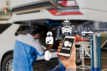 auto care application on smartphone with Blurred picture of car garage with cars being under maintenance and technicians for background