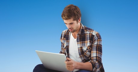 Young man using laptop over blue background