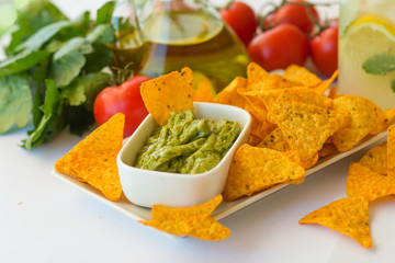 Homemade lemonade with salsa guacamole with corn chips and vegetables