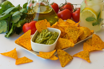 Homemade lemonade with salsa guacamole with corn chips and vegetables
