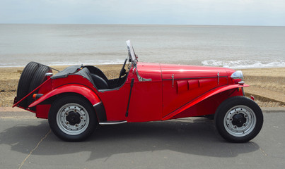  Classic Red Delon Sports - Trials Motor Car Parked on Seafront Promenade.