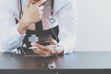 close up of smart medical doctor working with smart phone and stethoscope on dark wooden desk with virtual icon diagram