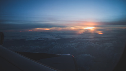 Sunset from 30000 feet wing party visible. Cold tones. Travel concept