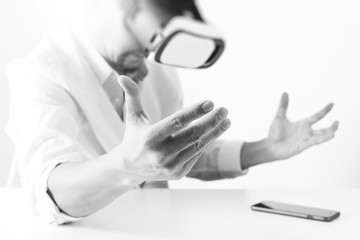 businessman wearing virtual reality goggles in modern office with Smartphone using with VR headset,black and white